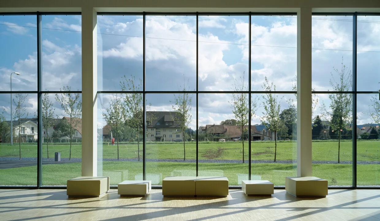 Large window overlooking meadow and buildings in the background