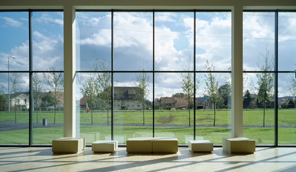 Großes Fenster mit Blick auf Wiese und Gebäude im Hintergrund