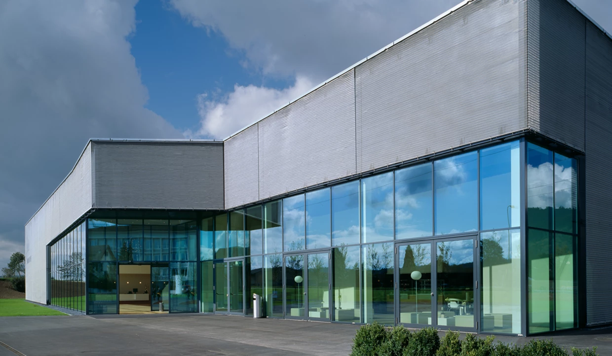 Modernes Gebäude mit Glasfassade und bewölktem Himmel