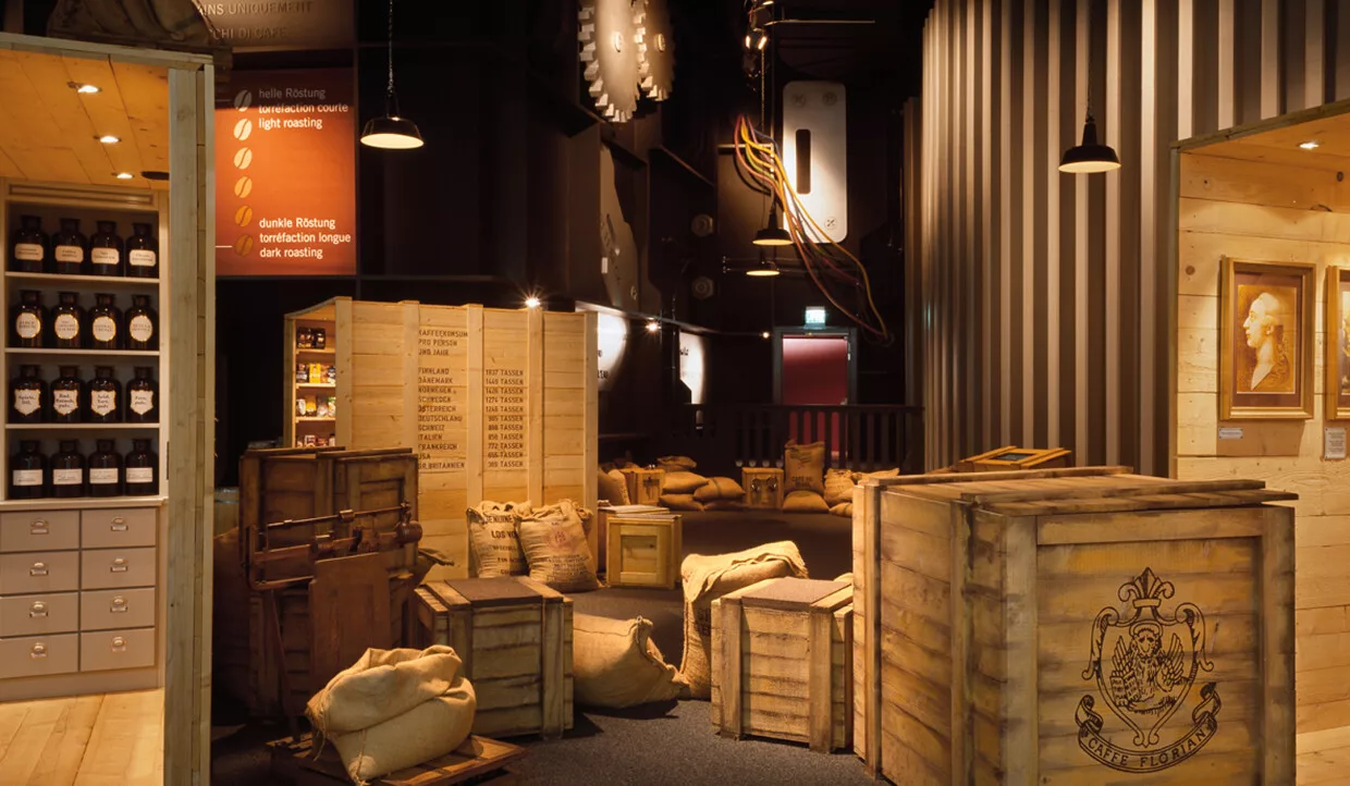 Holzkisten und Kaffeesäcke in einem abgedunkelten Ausstellungsraum