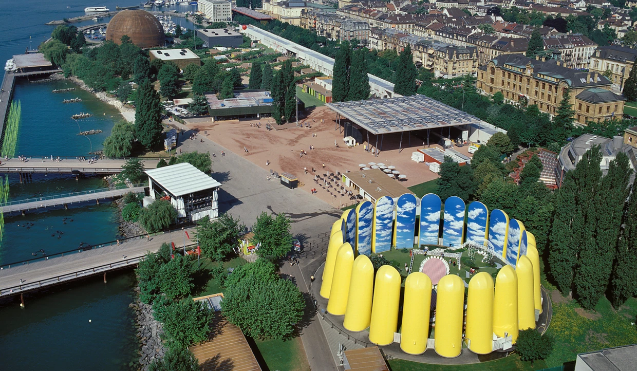 Luftaufnahme einer Ausstellung mit gelben Strukturen, Wasser, Brücken und Umgebung