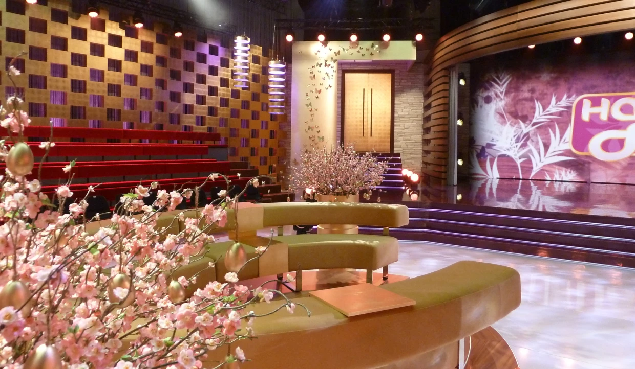 Stage with flower arrangement, seating, wall pattern, and lighting