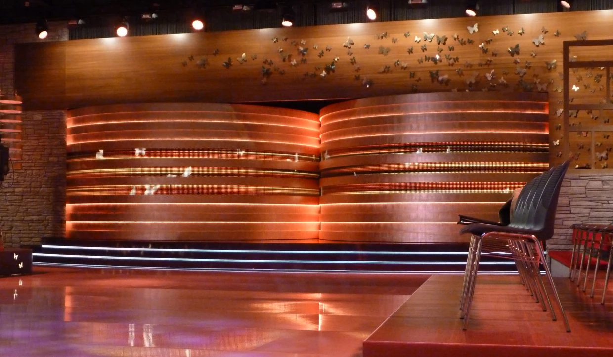 Stage with wood paneling, butterfly decor, empty chairs on the right