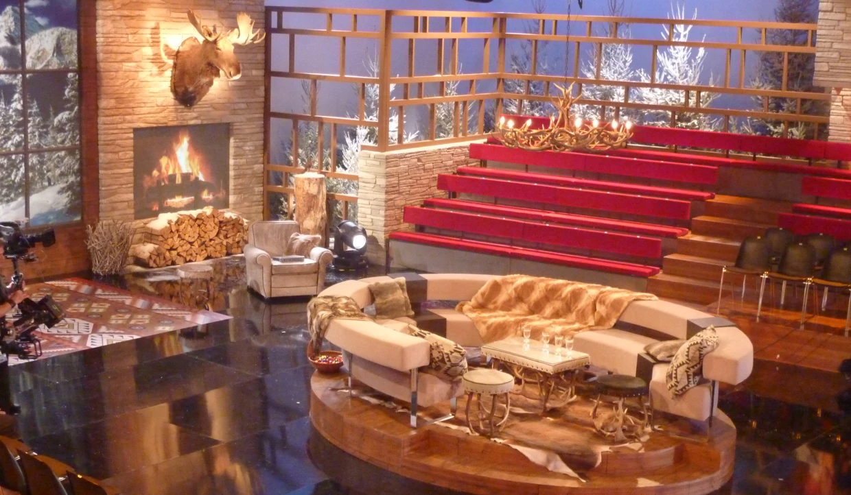 Stage set with fireplace, red seats, and round couch