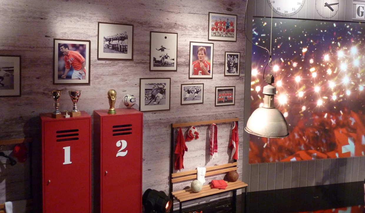Rot lackierte Spinde mit Pokalen und Fußballfotos an der Wand