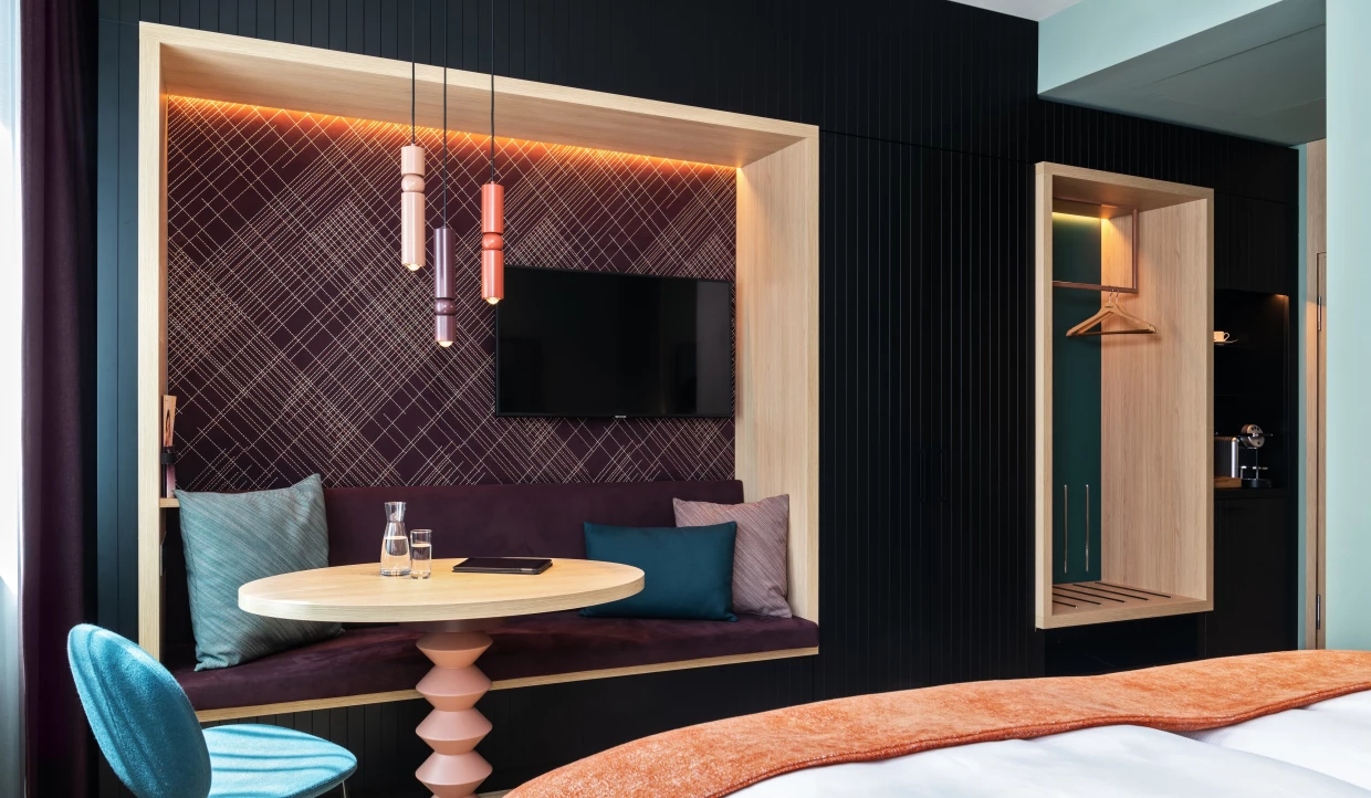 Stilvolle Designer Sitznische in einem Hotelzimmer mit violetter Wandbespannung mit diagonalen Stickereien.