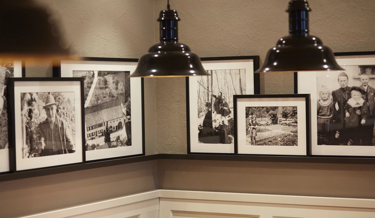 Detailaufnahme von Schwarz-Weiß-Fotografien an einer Wand neben einer schwarzen Pendelleuchte.