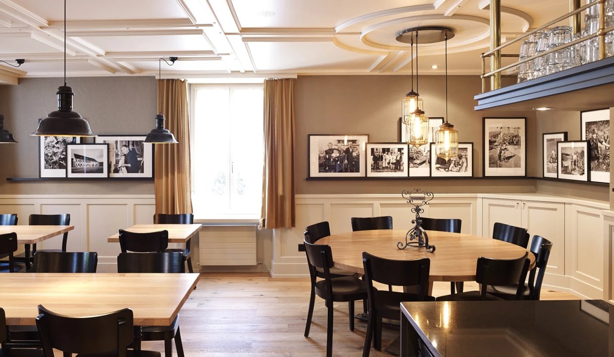 Elegante Essensecke mit Holztisch, schwarzen Stühlen und gerahmten Fotos an der Wand.