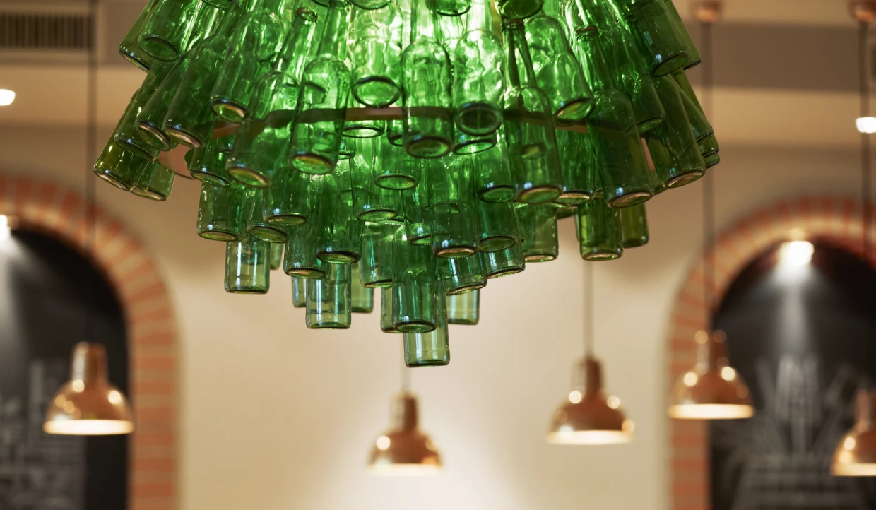 Lampe aus grünen Glasflaschen, darunter Kupferlampen.