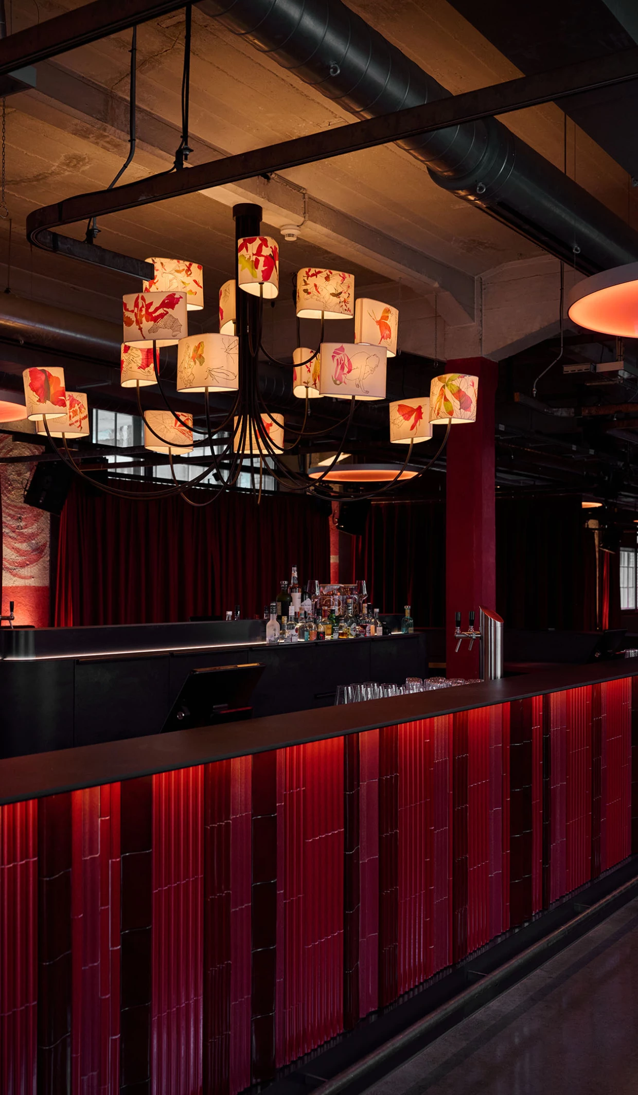 Moderne Bar mit roten Paneelen und dekorativen Deckenlampen