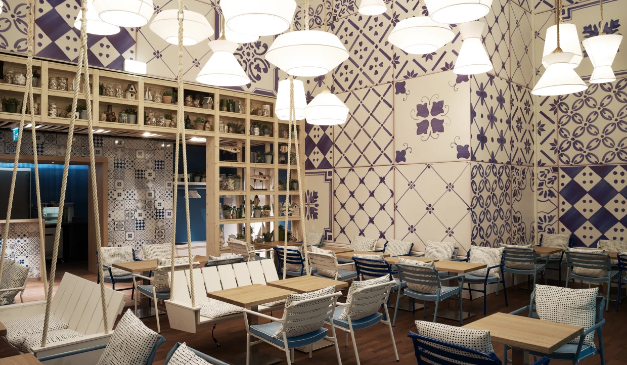 Restaurant mit blauen und weißen Fliesenmustern, Holztischen und Stühlen.