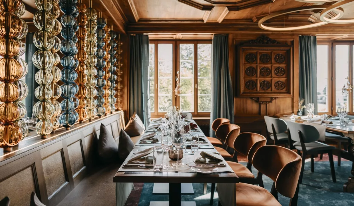 Interieur eines Landrestaurants mit Sitzbank aus Holz und Raumteiler aus buntem Glas