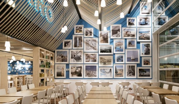Restaurant mit Holzdecken, blauen Wänden, Bildergalerie und weißen Stühlen.