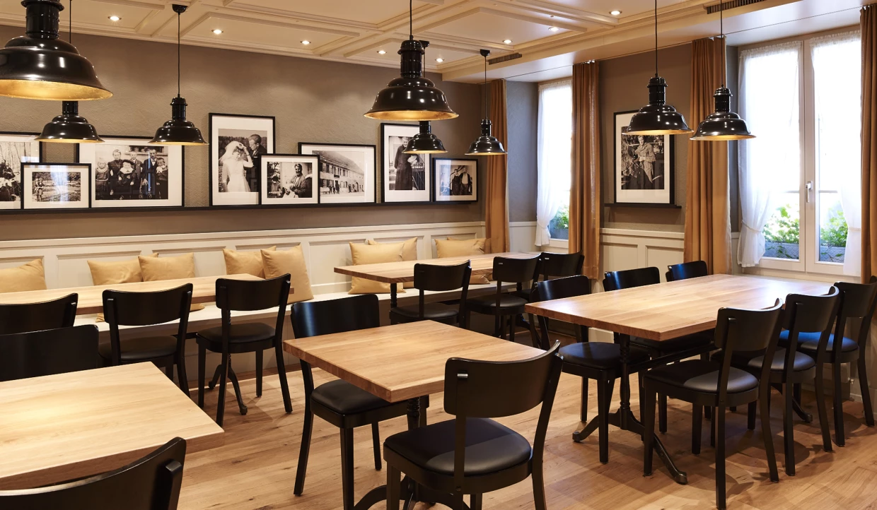 Dining area with wooden tables, black chairs, wall photos, and large pendant lights.