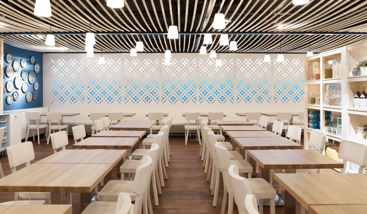 Dining area with white chairs, wooden tables, and blue wall plate decorations.