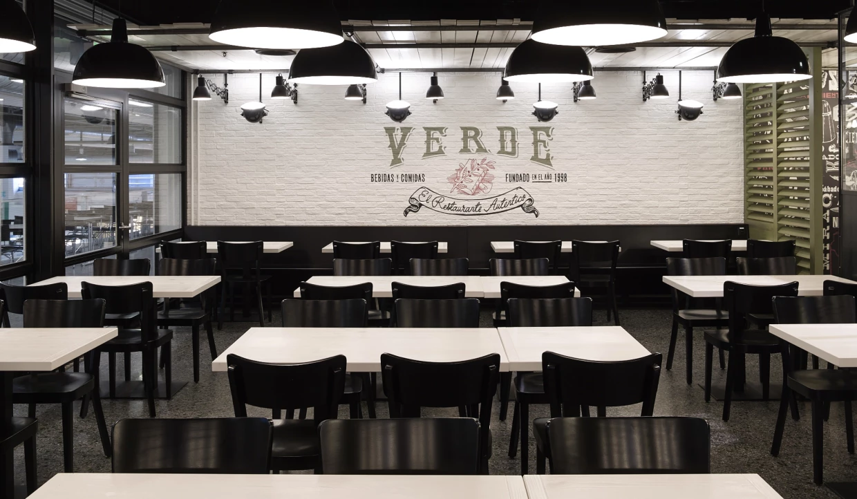 Restaurantinterieur mit schwarzen Stühlen und Verde-Logo an der Wand.