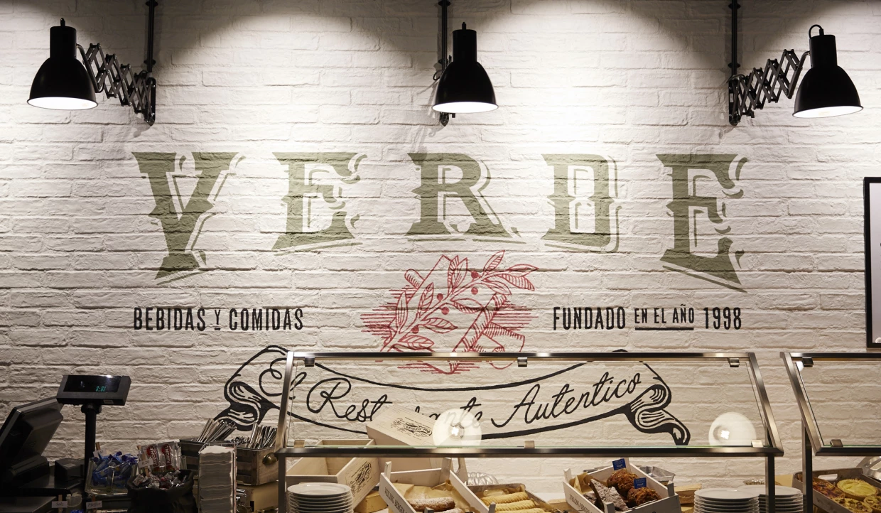 Wand im Restaurant mit dem Schriftzug 'Verde' und Dekoration.