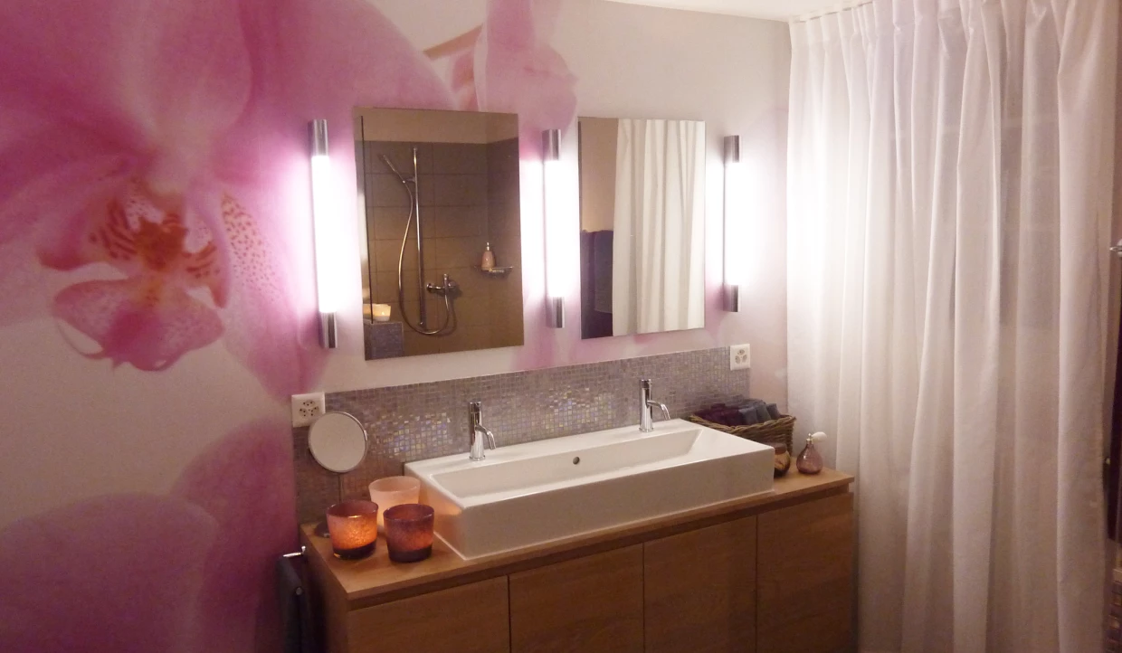 Badezimmer mit doppeltem Waschbecken, großer Spiegel und Orchideenmotiv an der Wand