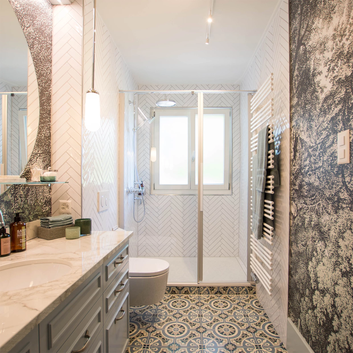 Badezimmer mit Dusche, Fenster, großem Spiegel und gemustertem Boden