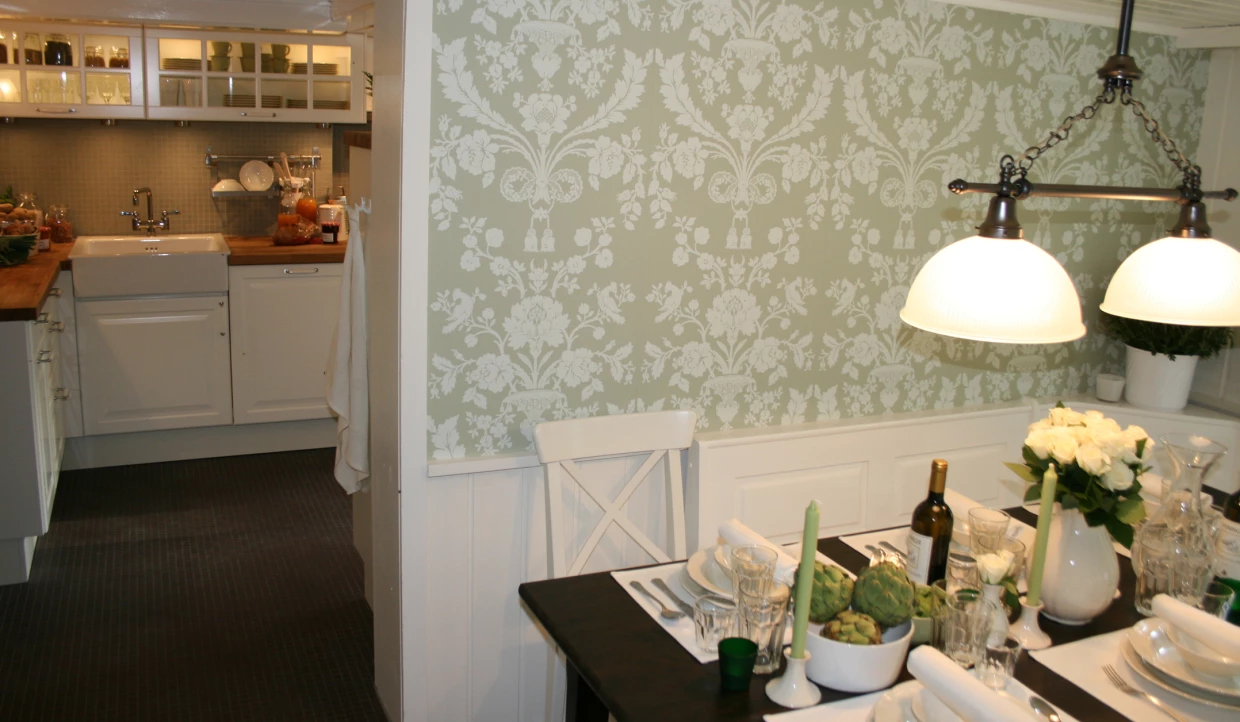 Esszimmer mit weißer Tapete, gedecktem Tisch und Lampe