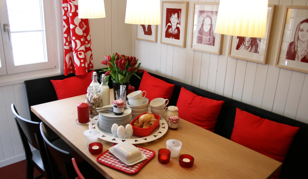 Frühstückstisch mit Geschirr, Tulpen und roten Kissen