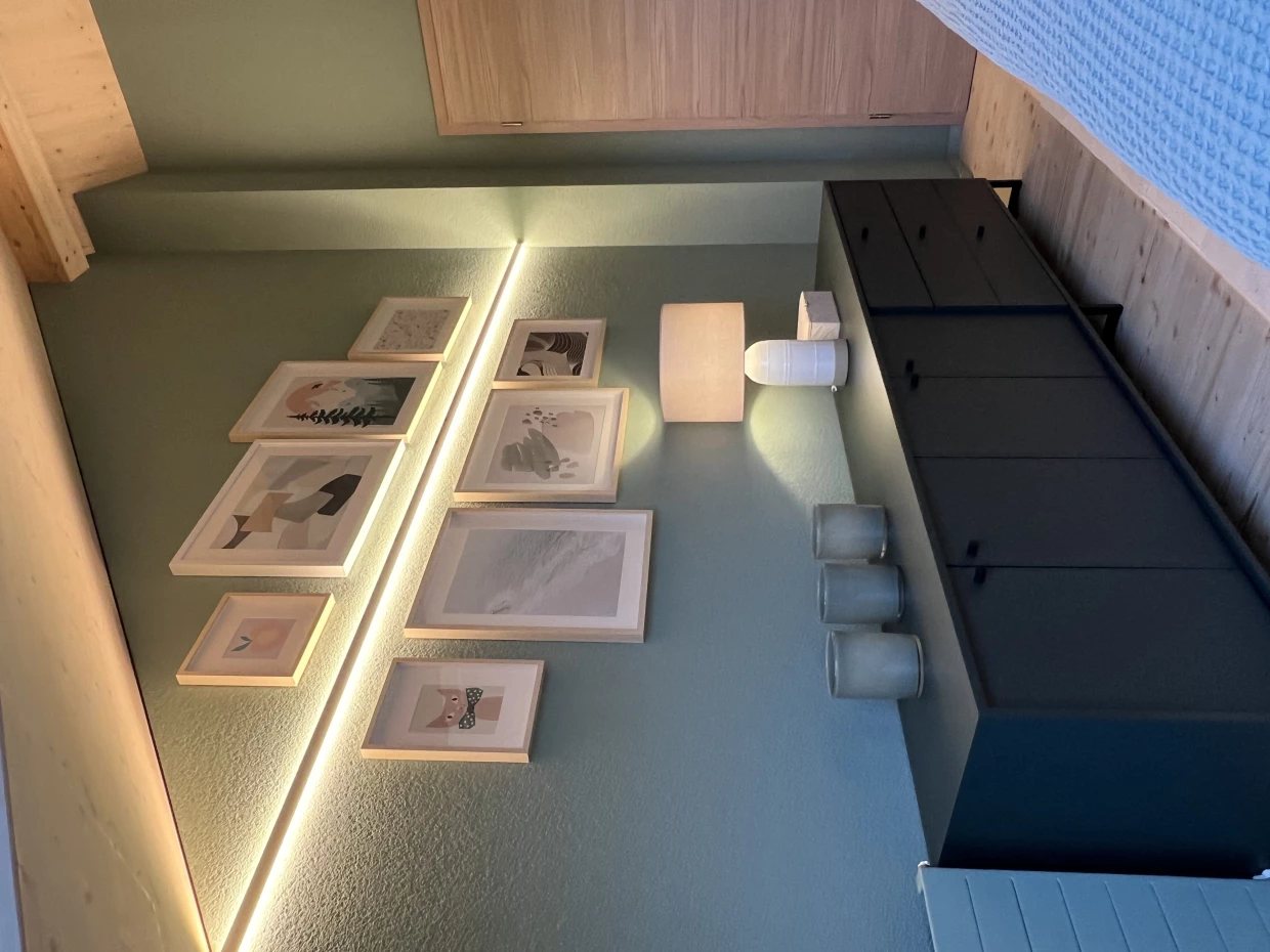 Galeriewand mit Bildern, dunkles Sideboard, Lampen