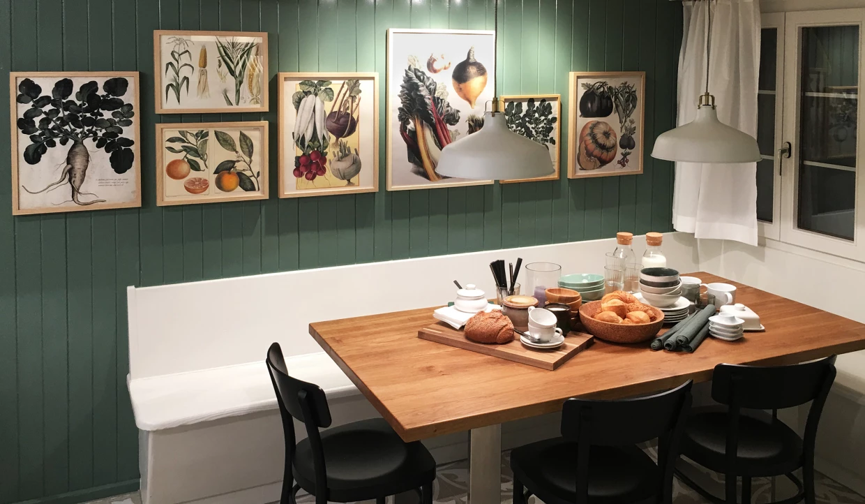Gemütliche Essecke mit Holztisch, Stühlen und botanischen Wandbildern