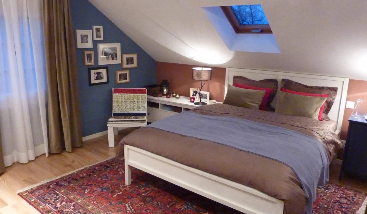 Gemütliches Schlafzimmer mit Dachschräge, Doppelbett, Bilderwand und Dachfenster
