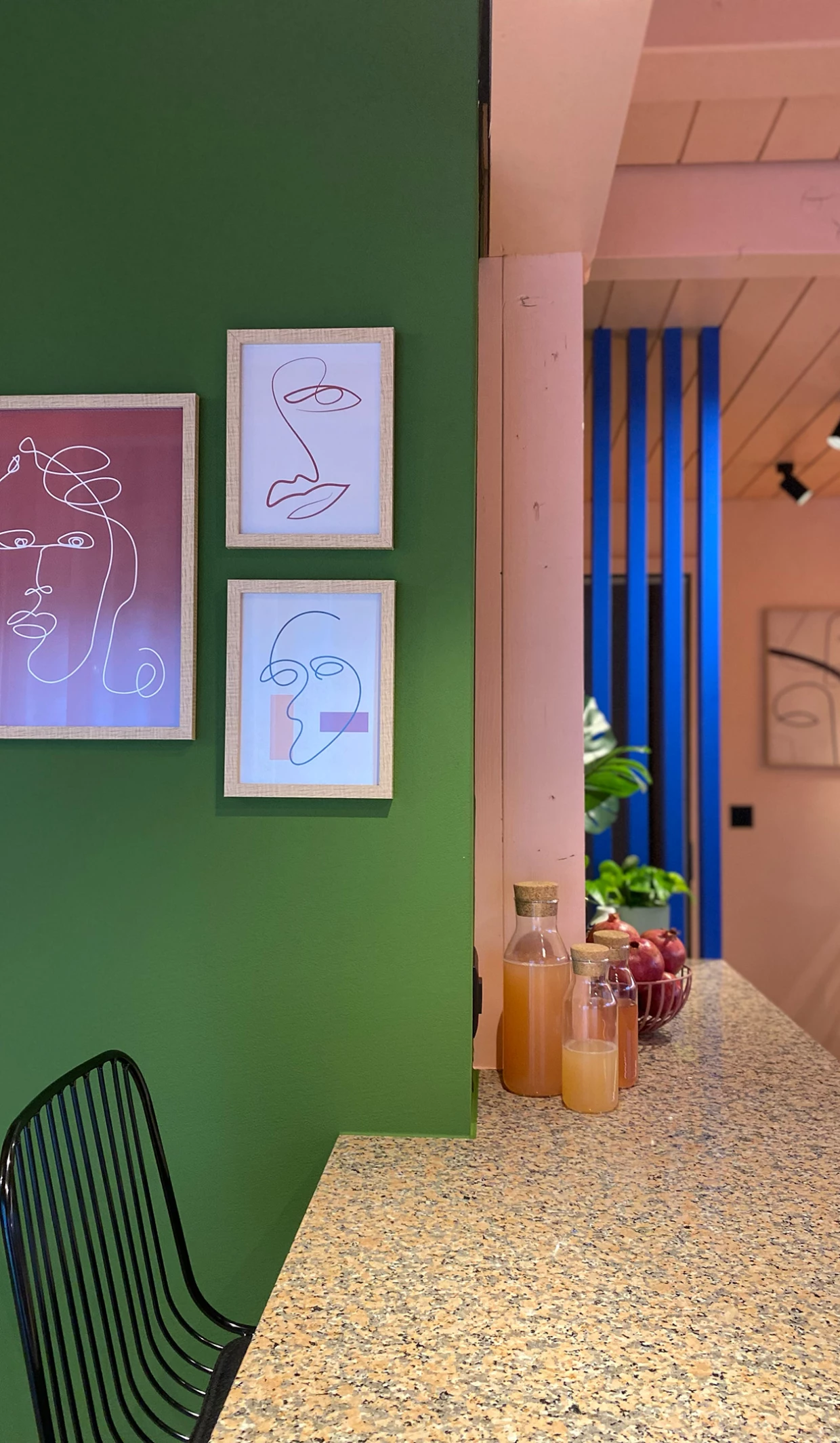 Grüne Wand mit drei minimalistischen Porträts und einer Bar mit Getränken