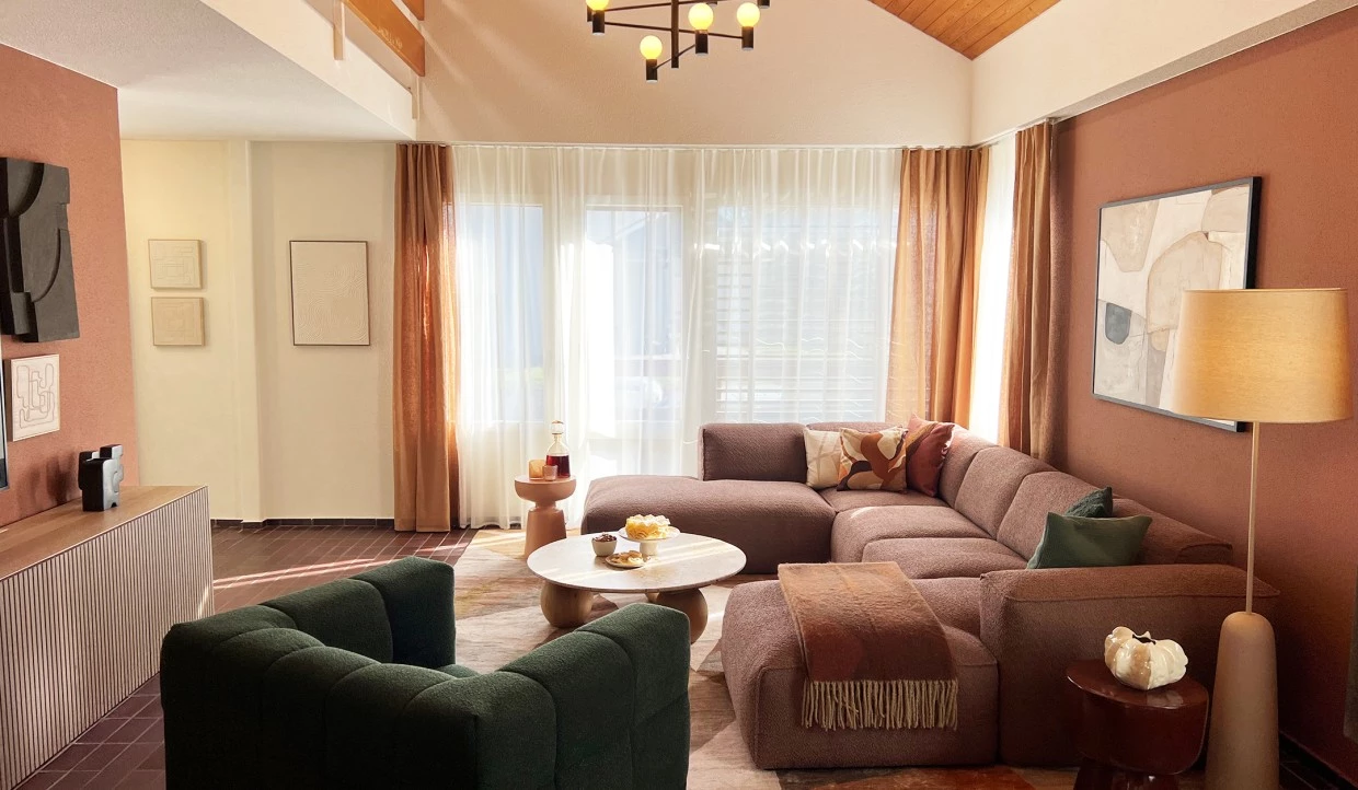 Helles Wohnzimmer mit Sofas, Vorhängen und einem Tisch in der Mitte