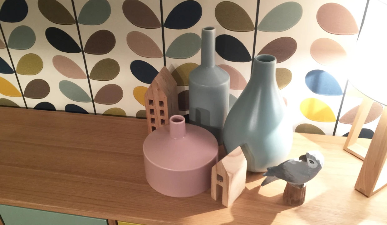 Holzvögel und Vasen auf Sideboard, bunte Tapete im Hintergrund