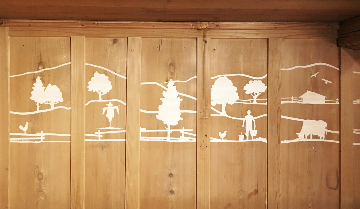 Holzwand mit ländlichen weißen Silhouetten von Bäumen und Tieren