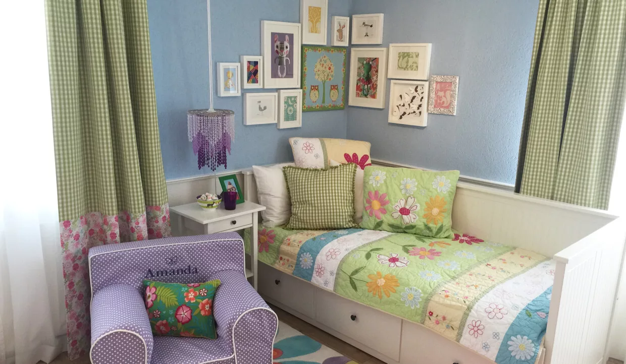 Kinderzimmer mit buntem Bett, blauen Wänden und Deko an der Wand