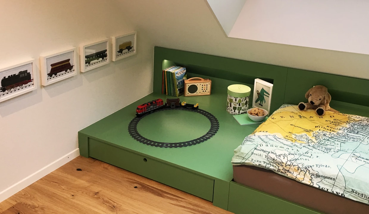 Kinderzimmer mit grünem Bett, Spielzeugzug und Landkartendecke