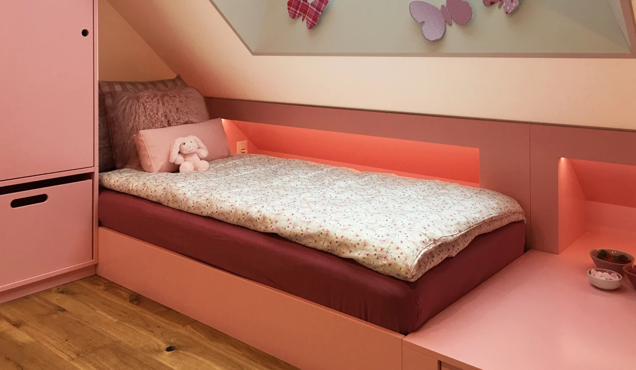 Kinderzimmer in Rosa mit Bett, Kissen und Schmetterlingswand