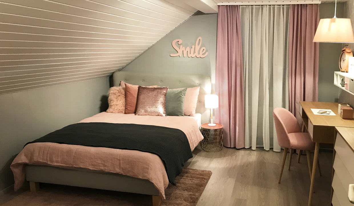 Bedroom with bed and desk under slanted ceiling