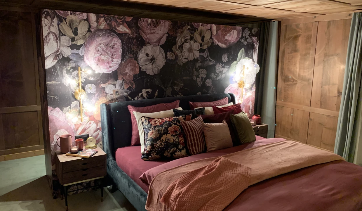 Schlafzimmer mit Blumenwandtapete und dekorativen Kissen