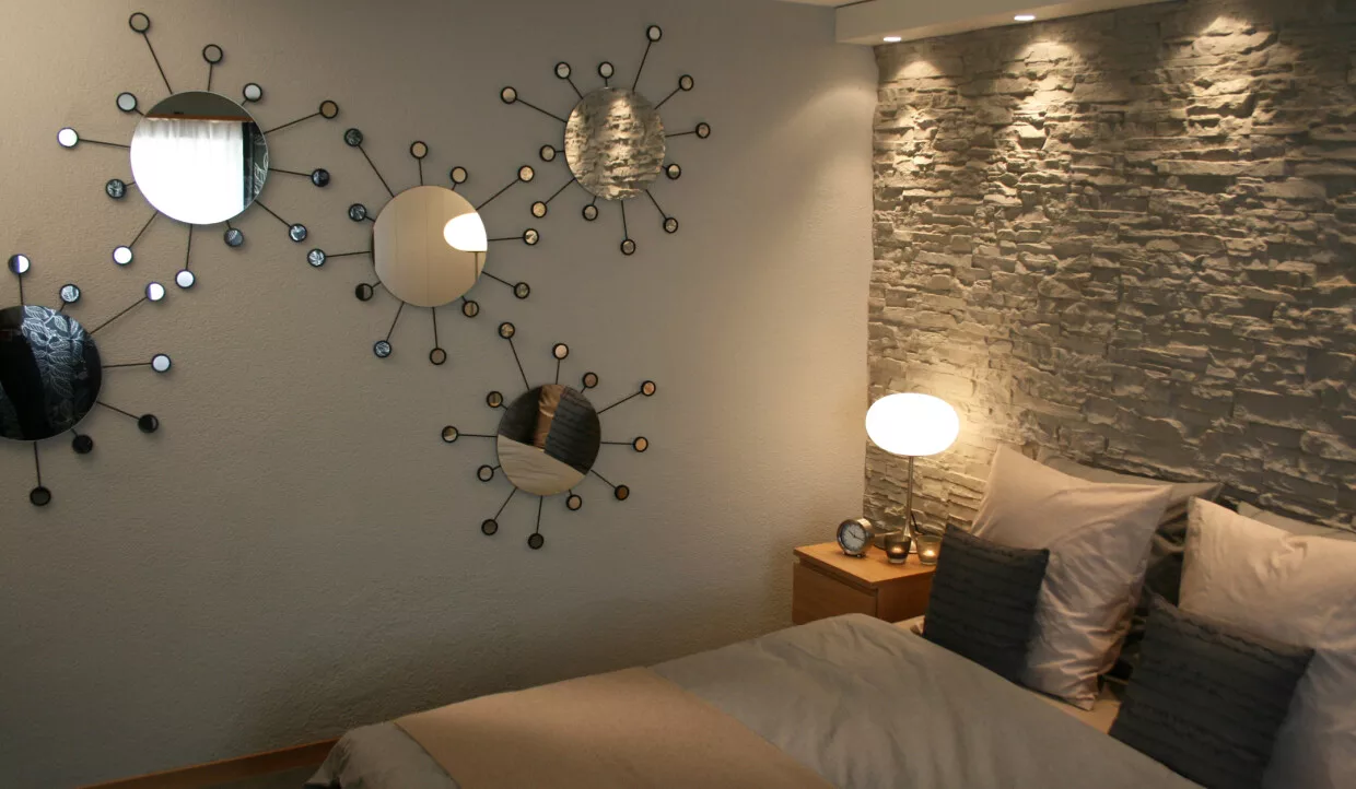 Schlafzimmer mit Dekospiegeln und Steinwand