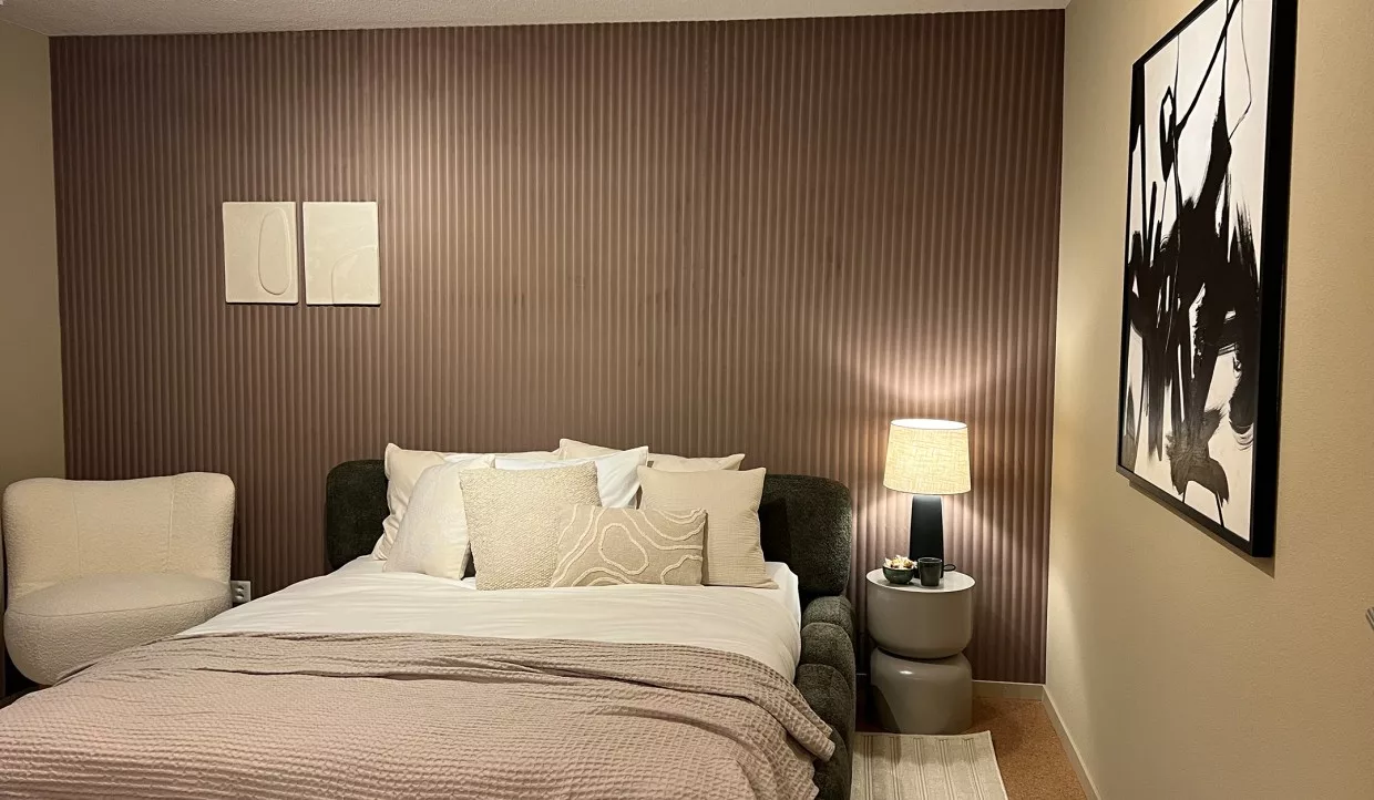 Schlafzimmer mit Doppelbett, Kissen, Nachttischlampe und zwei Wandbildern