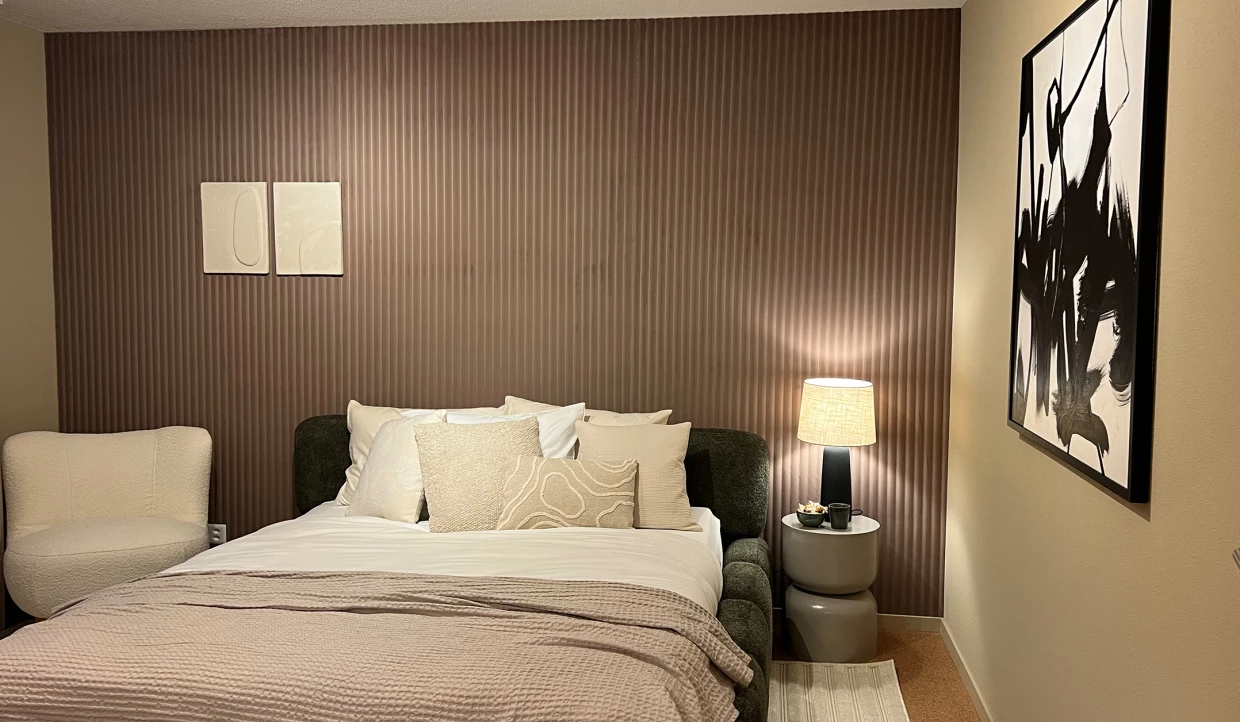Schlafzimmer mit Doppelbett, Kissen, Nachttischlampe und zwei Wandbildern