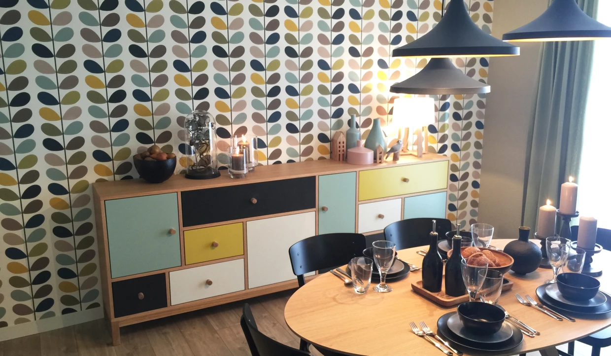 Sideboard mit bunten Fronten, gedeckter Esstisch mit Kerzenhalter