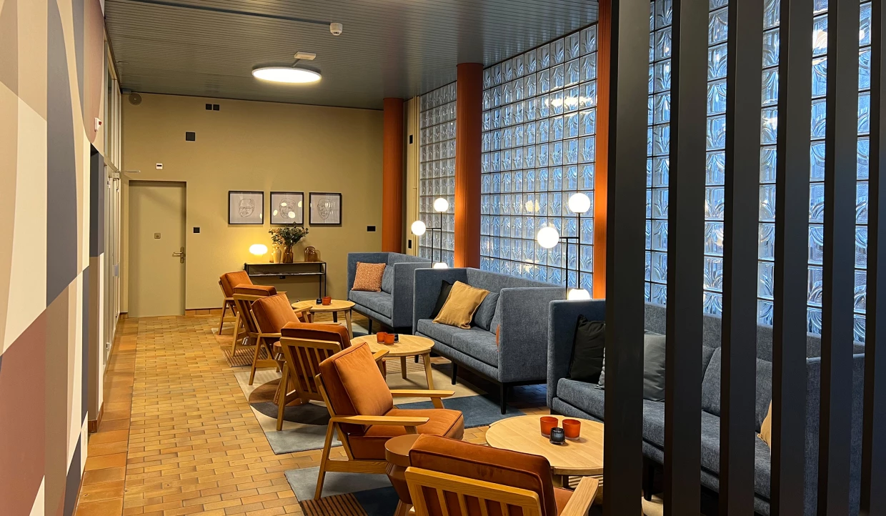 Sitzecke mit blauen Sofas und orangefarbenen Stühlen