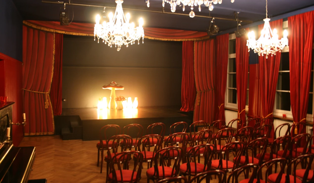Small theater hall with red curtain and chandeliers