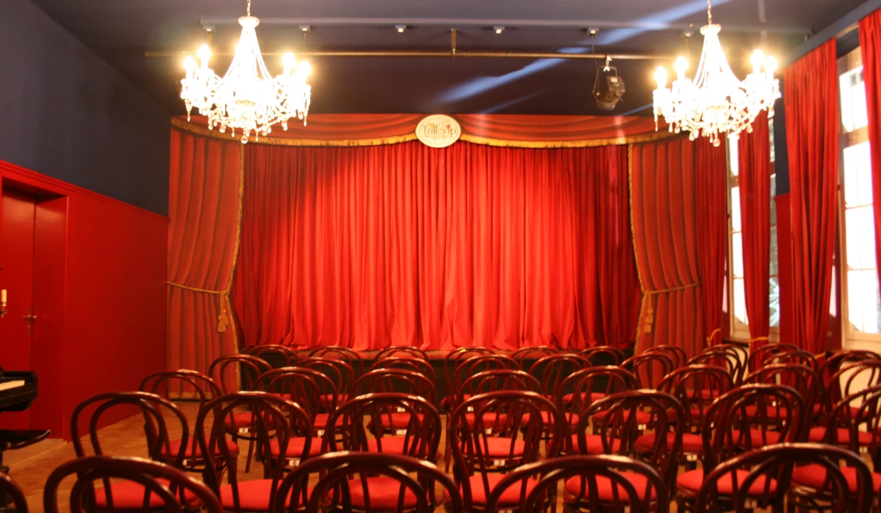 Theater hall with rows of chairs and closed red stage
