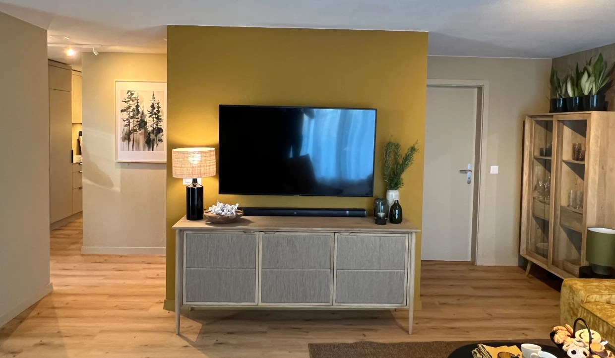 Wohnbereich mit Fernseher, gelber Wand und Dekorationen