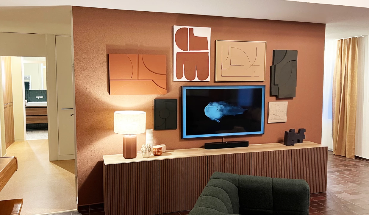 Wohnzimmer mit Fernseher, Kunst an der Wand und Lampe auf Holzkonsole