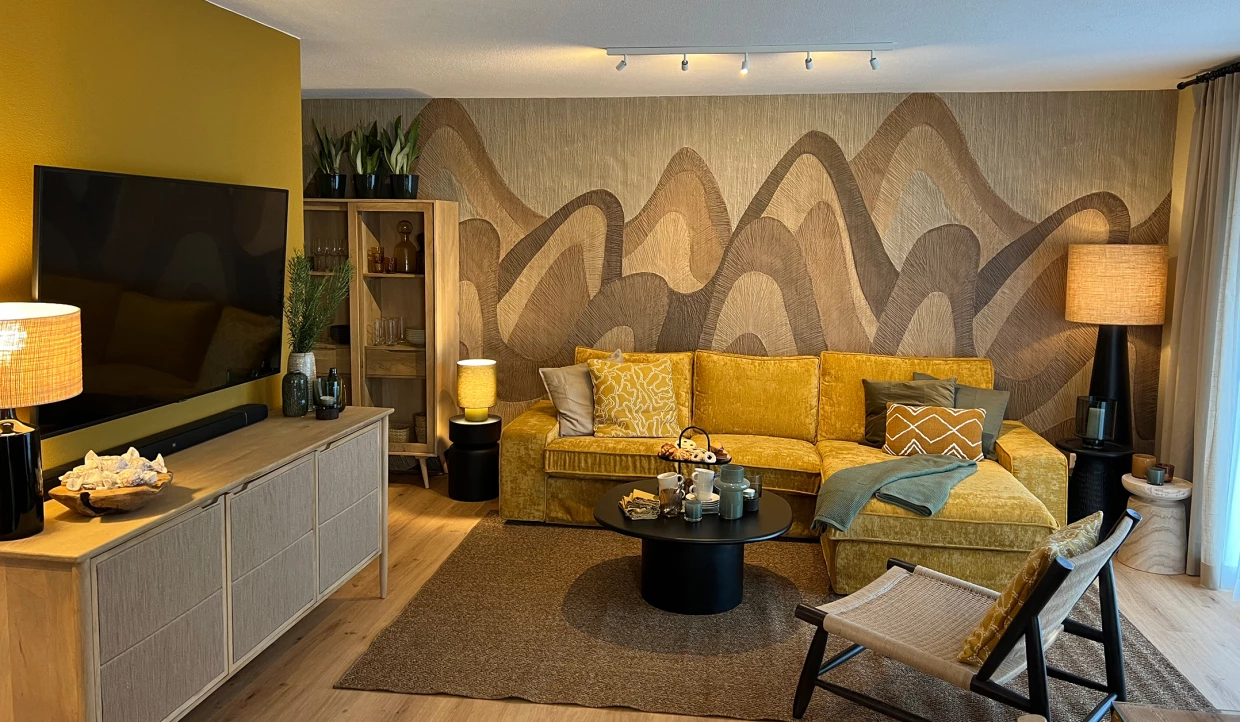 Wohnzimmer mit gelbem Sofa, Mustertapete und Fernseher