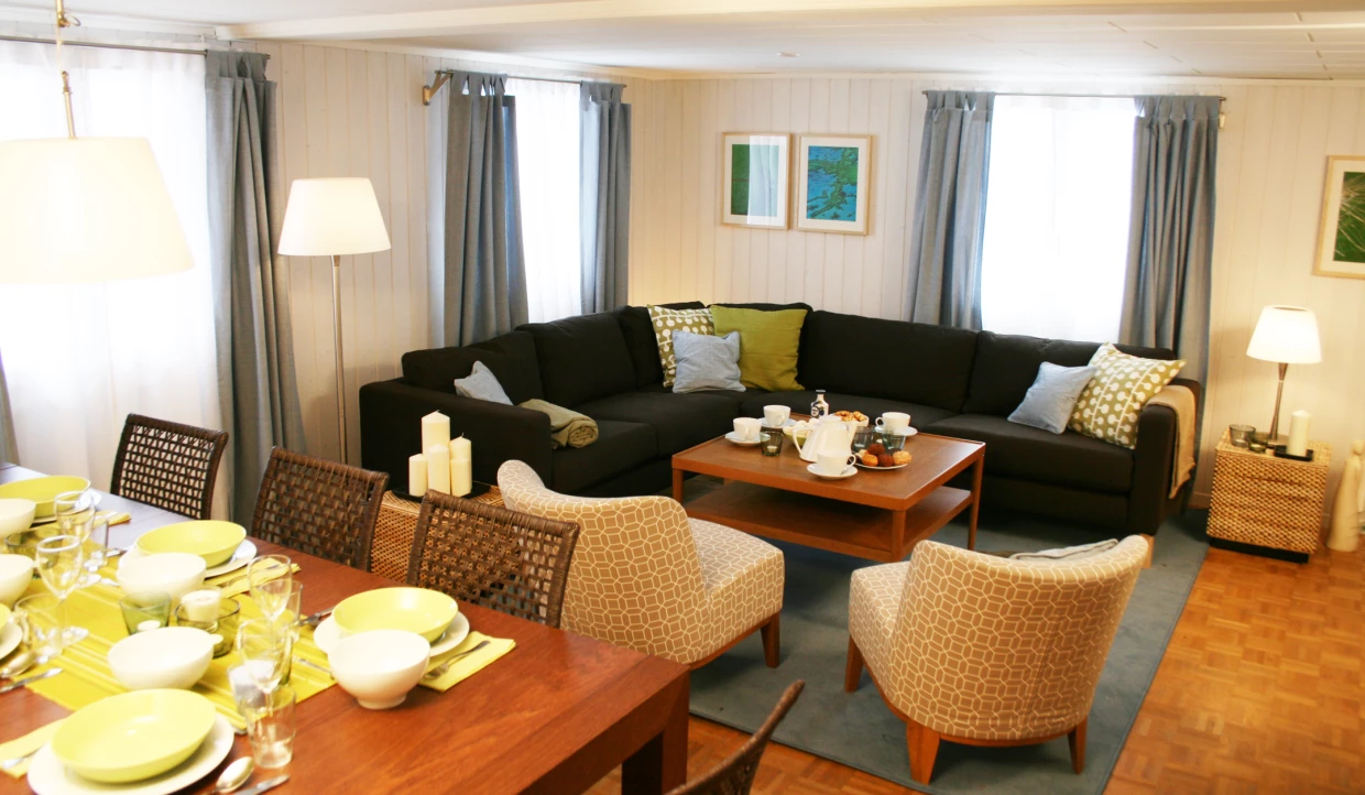 Wohnzimmer mit schwarzem Sofa, Esstisch und grünen Akzenten