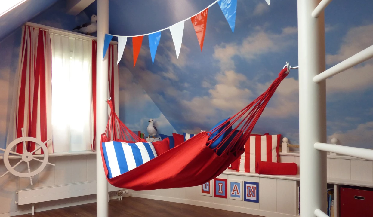 Zimmer mit Hängematte, blau-roten Kissen und Wimpelkette
