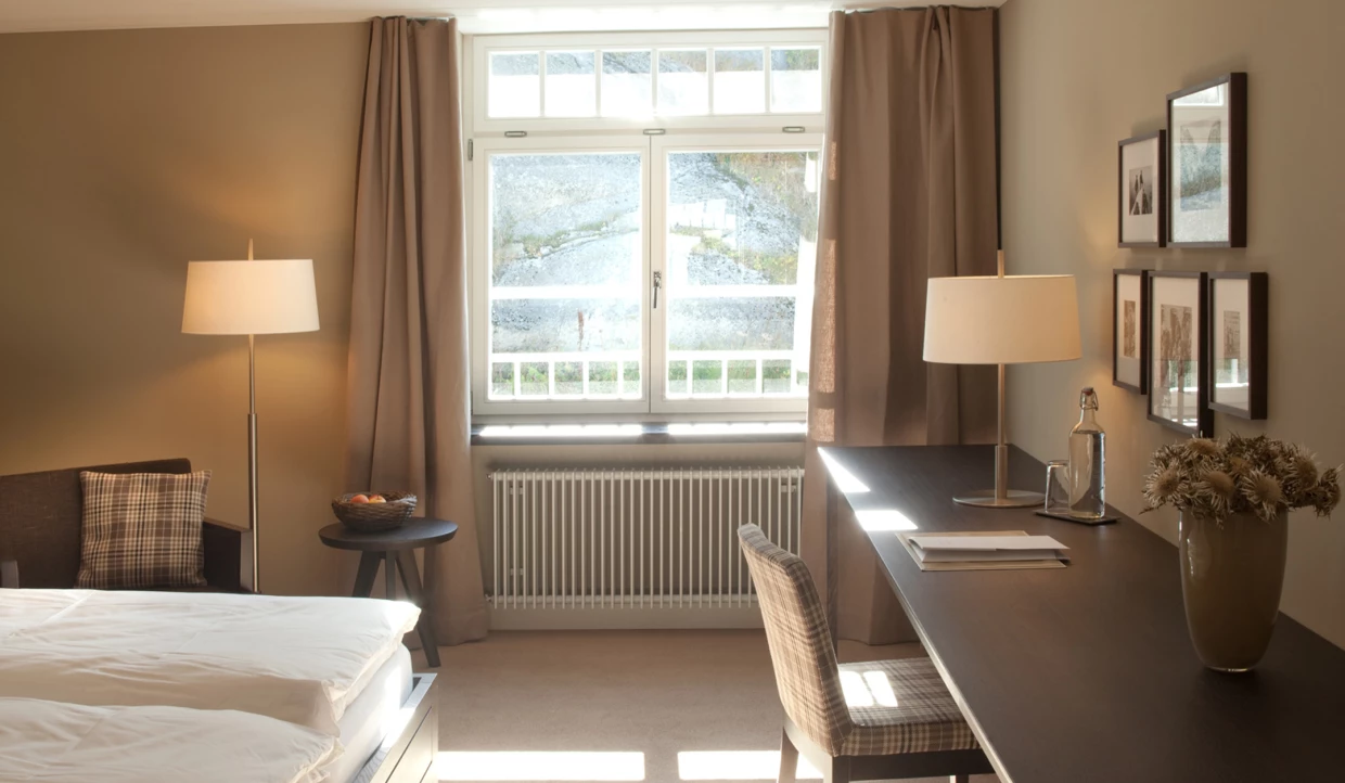 Arbeitsbereich im Schlafzimmer mit Schreibtisch und Lampe.